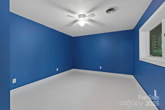 an empty room with windows and fan