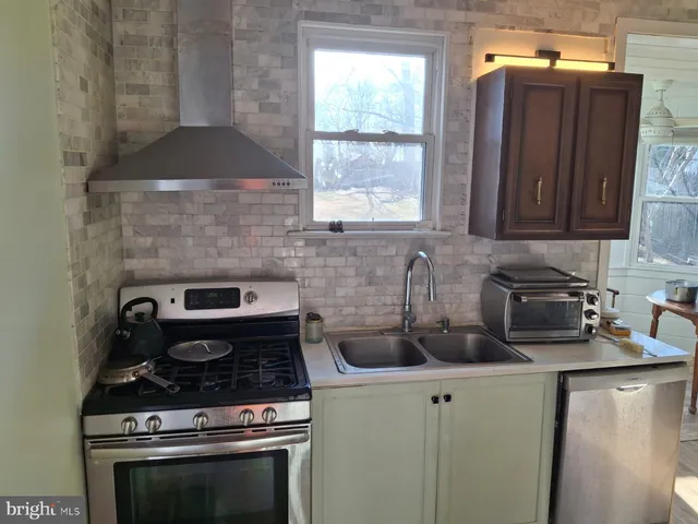 a kitchen with a stove a sink a window and cabinets