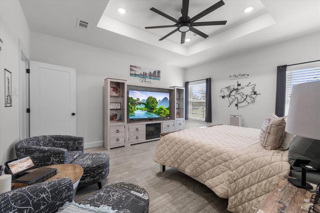 1039 Monaco Court Springtown, TX 76082 - Photo 13 of 33 Primary bedroom featuring wood-tile flooring, a tray ceiling, and recessed lighting.