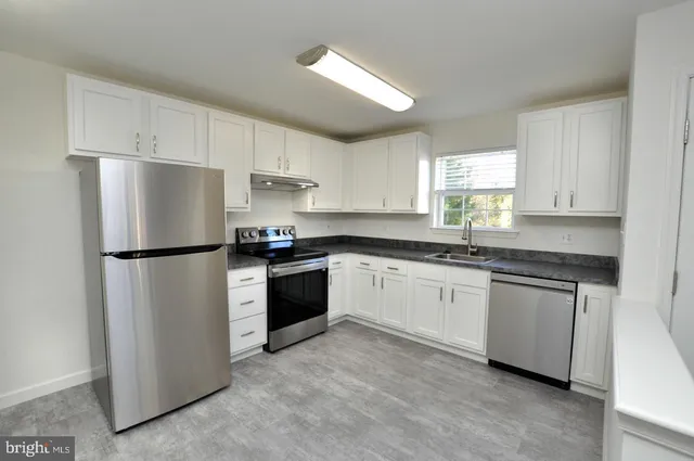 a kitchen with granite countertop white cabinets and refrigerator