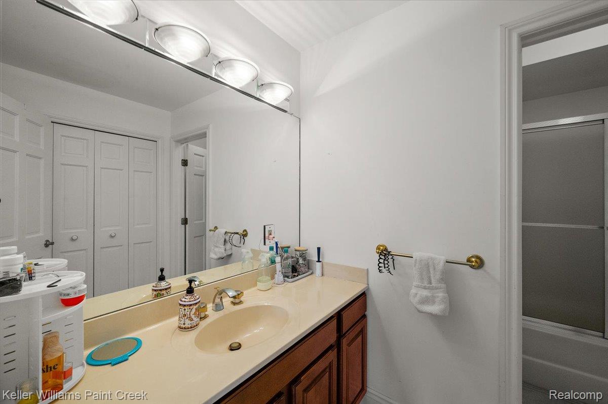 69069 Campground Road Romeo, MI 48065 - Photo 54 of 78 Bathroom vanity with an integrated sink, a light-toned countertop, and a large wall-mounted mirror