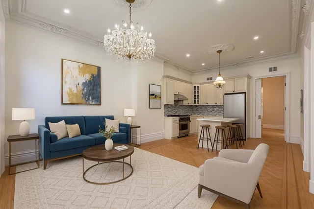 a living room with furniture kitchen view and a chandelier