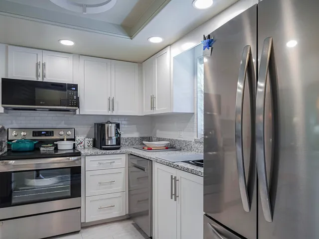 a kitchen with stainless steel appliances granite countertop a refrigerator and a sink