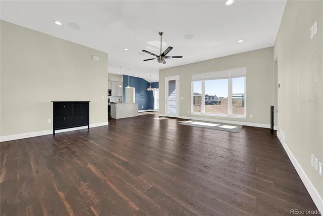 an empty room with wooden floor fireplace and windows
