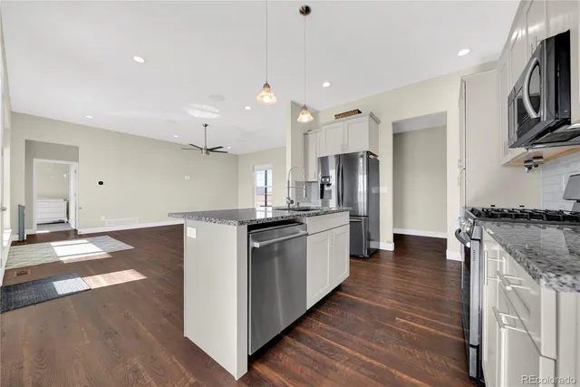 a kitchen with stainless steel appliances granite countertop a refrigerator a stove and a sink