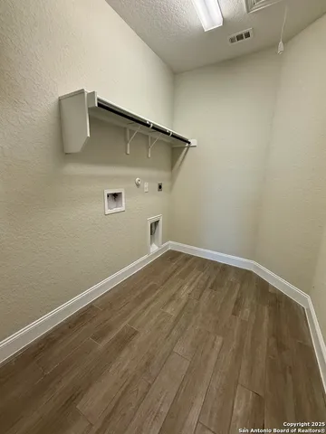 a view of an empty room with wooden floor and cabinet