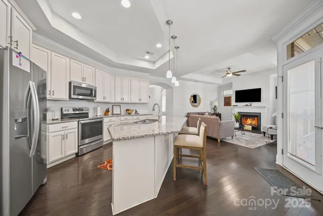 a kitchen with stainless steel appliances a microwave a stove a sink dishwasher a refrigerator white cabinets and wooden floor