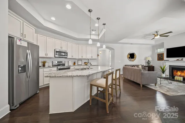 a kitchen with stainless steel appliances a stove a sink a refrigerator and a fireplace