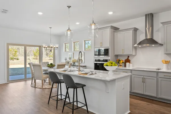 a kitchen with stainless steel appliances kitchen island granite countertop a sink a stove a dining table and chairs