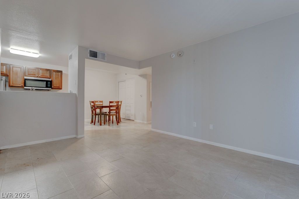7885 West Flamingo Road, Unit 1016 Las Vegas, NV 89147 - Photo 5 of 24 Functional kitchen with warm wood cabinetry overlooks the dining area, featuring practical tiled flooring throughout.
