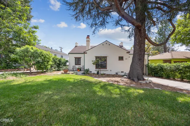 a view of a house with a yard and a large tree