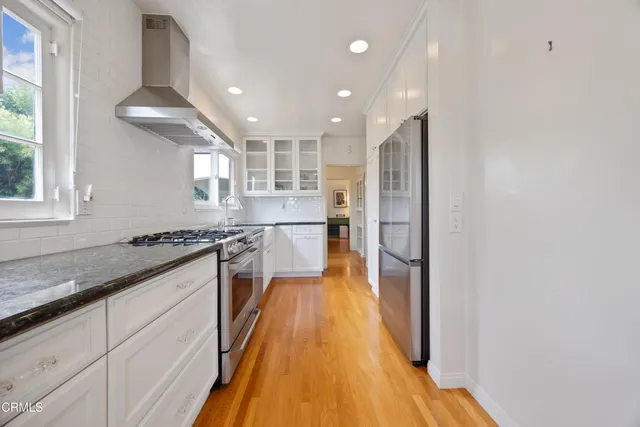a kitchen with stainless steel appliances granite countertop a sink and wooden floor