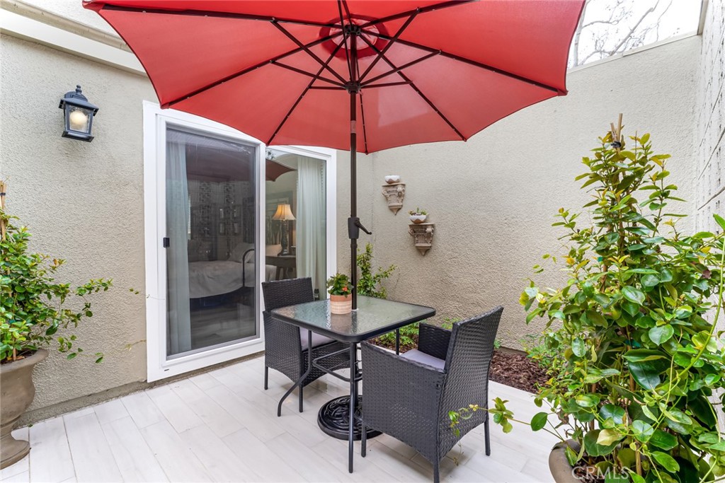 74 Calle Aragon, Unit B Laguna Woods, CA 92637 - Photo 4 of 22 a patio with a table and chairs under an umbrella