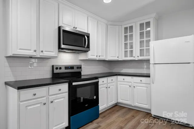 a kitchen with granite countertop white cabinets and black appliances