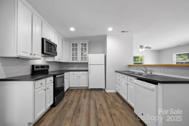 a kitchen with stainless steel appliances granite countertop a stove top oven a sink dishwasher and a refrigerator with wooden floor