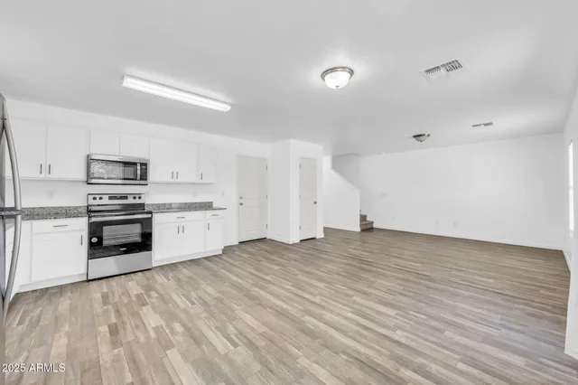 a view of empty room with wooden floor and window