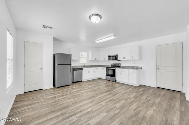 an empty room with wooden floor and windows