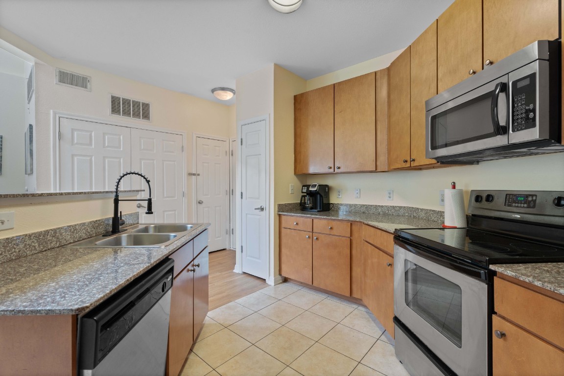 2502 Leon Street, Unit 501 Austin, TX 78705 - Photo 8 of 14 Kitchen featuring stainless steel appliances, light tile patterned flooring, and brown cabinetry