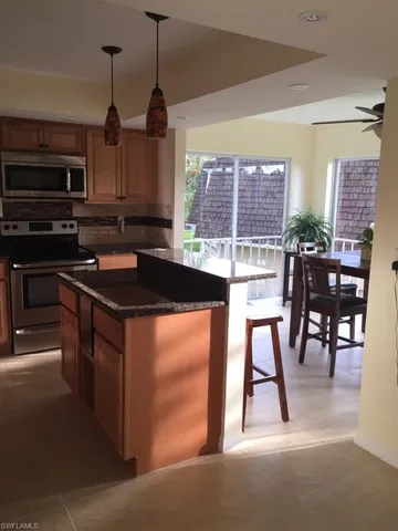 a kitchen with kitchen island granite countertop a stove top oven a sink a dining table and chairs with wooden floor