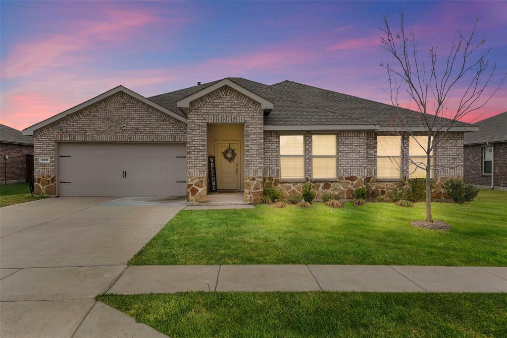 Ranch-style home featuring brick siding, a garage, a shingled roof, concrete driveway, and a yard