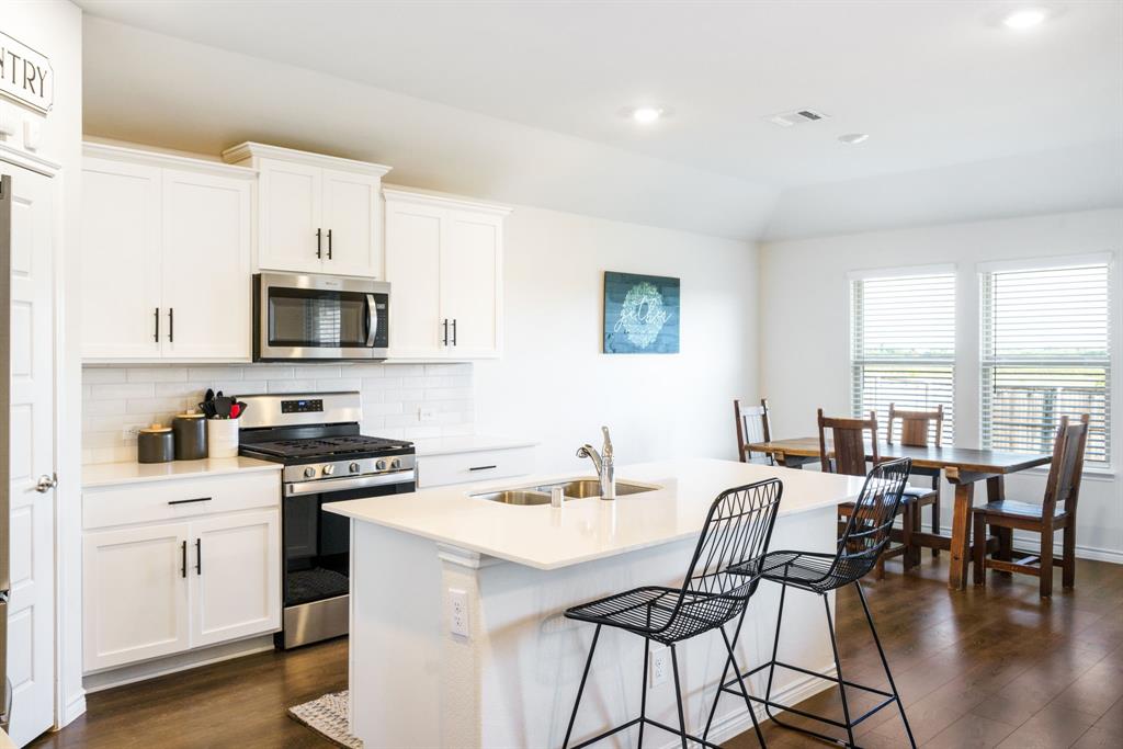 653 Bunker Hill Road Houston, TX 77024 - Photo 10 of 36 Kitchen with stainless steel appliances, a kitchen island with sink, white cabinets, tasteful backsplash, and dark wood-style flooring