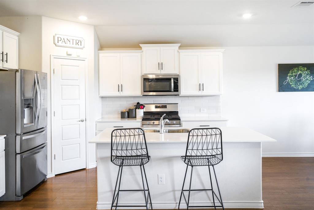 653 Bunker Hill Road Houston, TX 77024 - Photo 11 of 36 Kitchen with stainless steel appliances, white cabinets, an island with sink, backsplash, and recessed lighting