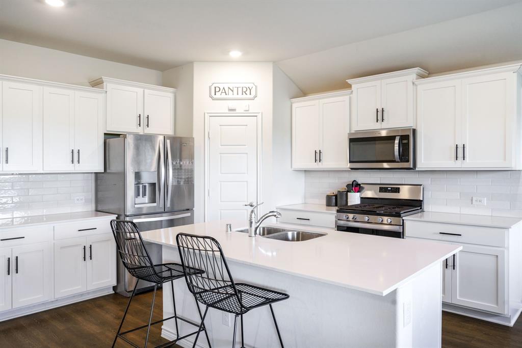 653 Bunker Hill Road Houston, TX 77024 - Photo 3 of 36 Kitchen with stainless steel appliances, a kitchen island with sink, dark wood-style floors, backsplash, and recessed lighting