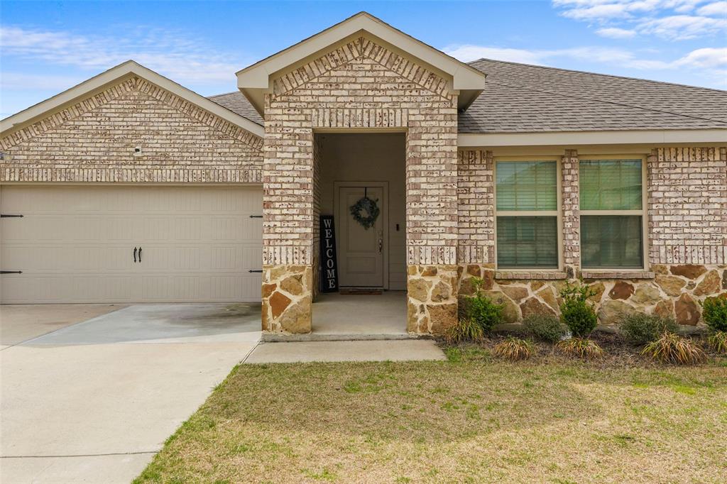 653 Bunker Hill Road Houston, TX 77024 - Photo 6 of 36 Single story home with stone siding, a garage, brick siding, driveway, and roof with shingles