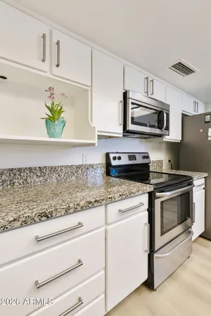 a kitchen with stainless steel appliances granite countertop white cabinets a stove a microwave and a sink