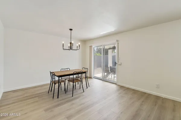 a dining room with wooden floor a chandelier a wooden table and chairs