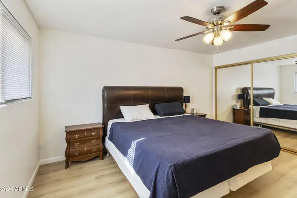 a bedroom with a bed and dresser with wooden floor