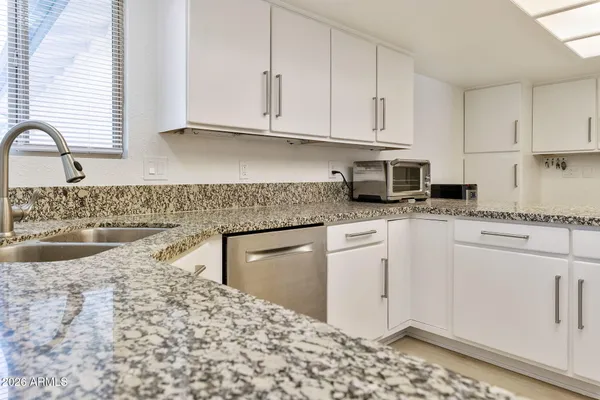 a kitchen with granite countertop white cabinets and white appliances