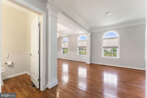 a view of an empty room with window and wooden floor