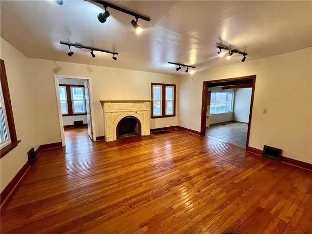 an empty room with wooden floor and a fireplace