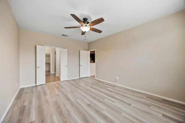 a view of empty room with wooden floor and ceiling fan