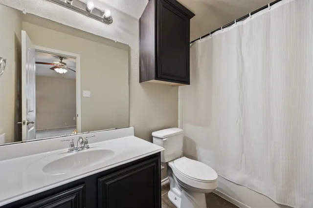 a bathroom with a granite countertop sink and a toilet