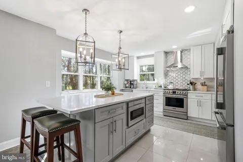 a kitchen that has a lot of white cabinets and stainless steel appliances