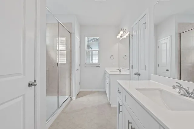 a spacious bathroom with a double vanity sink a mirror and a shower