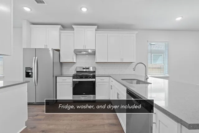 a kitchen with stainless steel appliances granite countertop a stove a refrigerator and a sink
