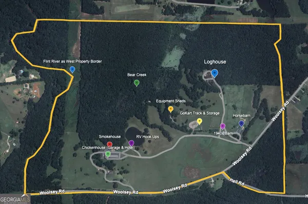 an aerial view of a house with outdoor space and trees all around