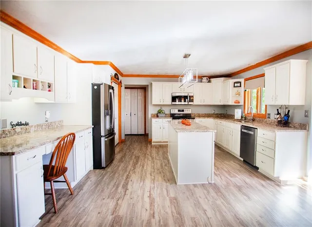 a kitchen with a refrigerator a stove top oven a sink dishwasher and white cabinets with wooden floor