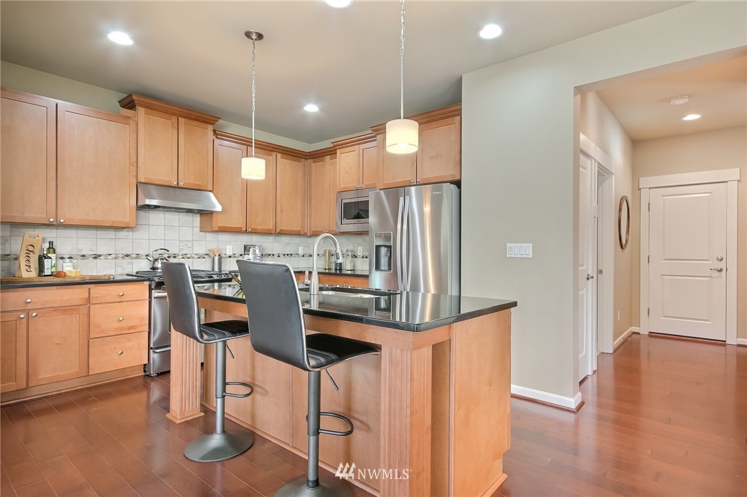 21809 38th Drive Southeast Bothell, WA 98021 - Photo 8 of 27 a kitchen with granite countertop a refrigerator a sink a stove a dining table and chairs