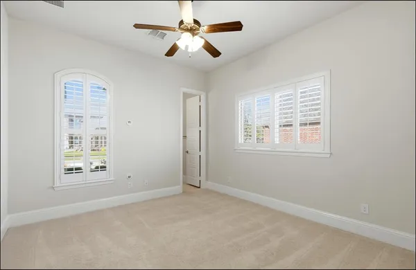 an empty room with windows and fan