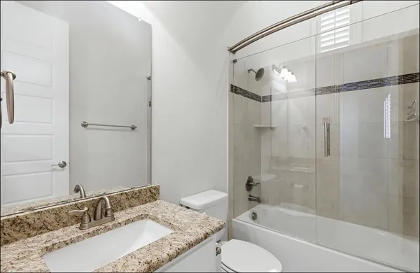 a bathroom with a granite countertop tub sink and mirror