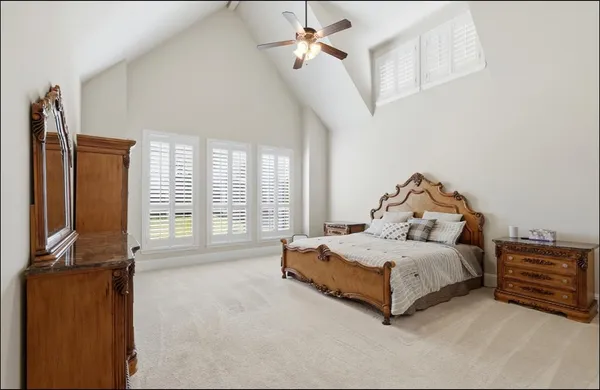 a spacious bedroom with a bed a couch and a chandelier