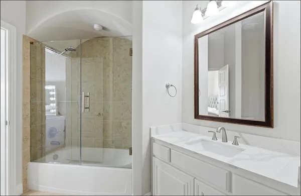 a bathroom with a shower sink and mirror with bathtub