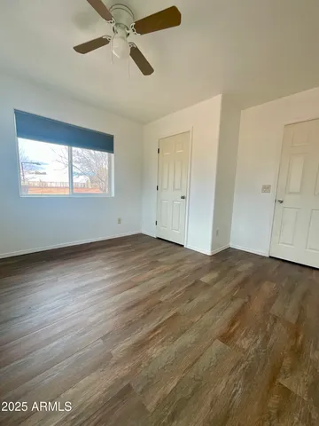 a view of empty room with wooden floor and fan