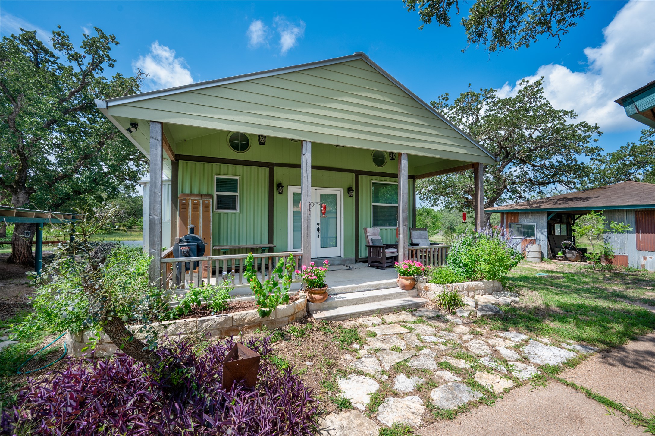 270 Dry Creek Road Manor, TX 78653 - Photo 4 of 40 A quaint ranch home with a welcoming front porch and a flagstone path, set amidst a vibrant, green landscape.