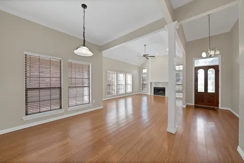 a view of an empty room with wooden floor and a fireplace