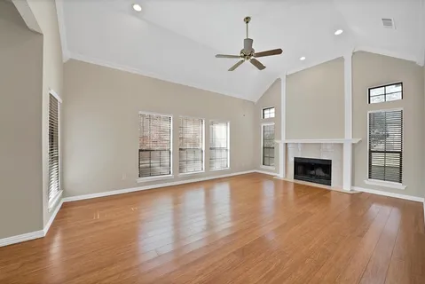 a view of an empty room with wooden floor fireplace and a window